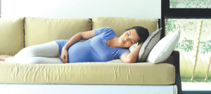 A pregnant woman sleeping peacefully on her side on a couch