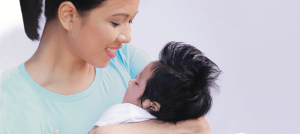 a mother cradling her infant in her arms to help a baby fall asleep faster.