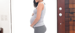 A pregnant woman cradling her belly while wondering what do babies dream about in the womb.